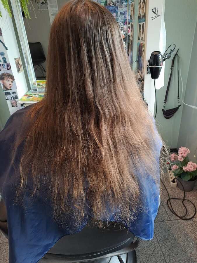 Asiakkaan pitkät hiukset takaa kuvattuna ennen käsittelyä